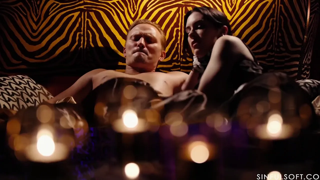 MILF Anna De Ville leads threesome with two men in a dark, candlelit room