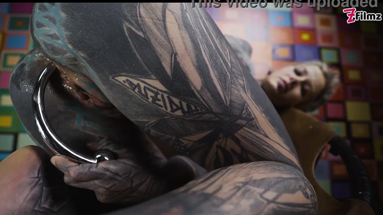 Anuskatzz, heavily tattooed and in a corset, masturbates her anus with a steel toy