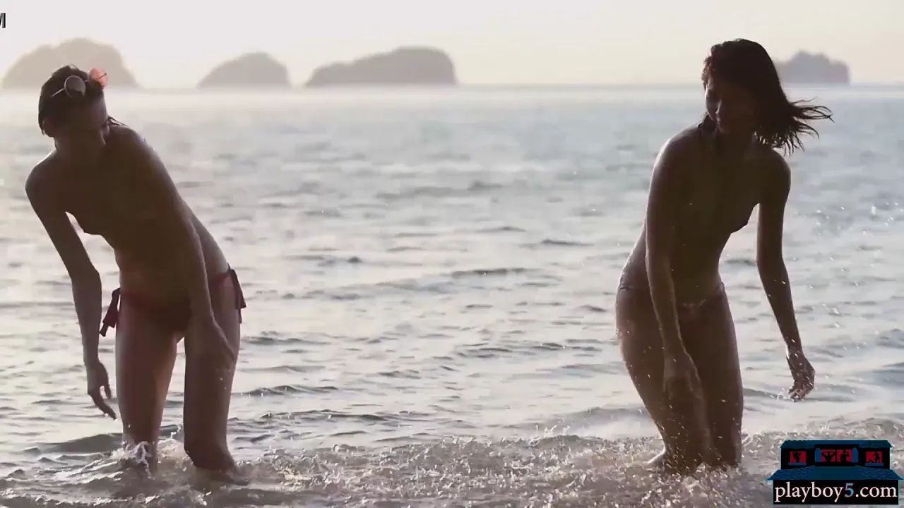 Asian and European petite lesbians play in the ocean in bikinis